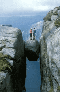 men standing on balanced rock