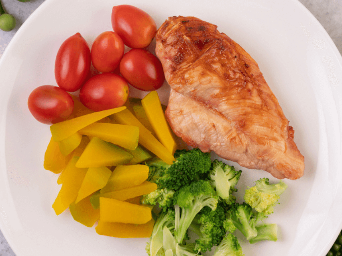 Mix of Vegetable and one piece of Chicken Breast on a White Plate