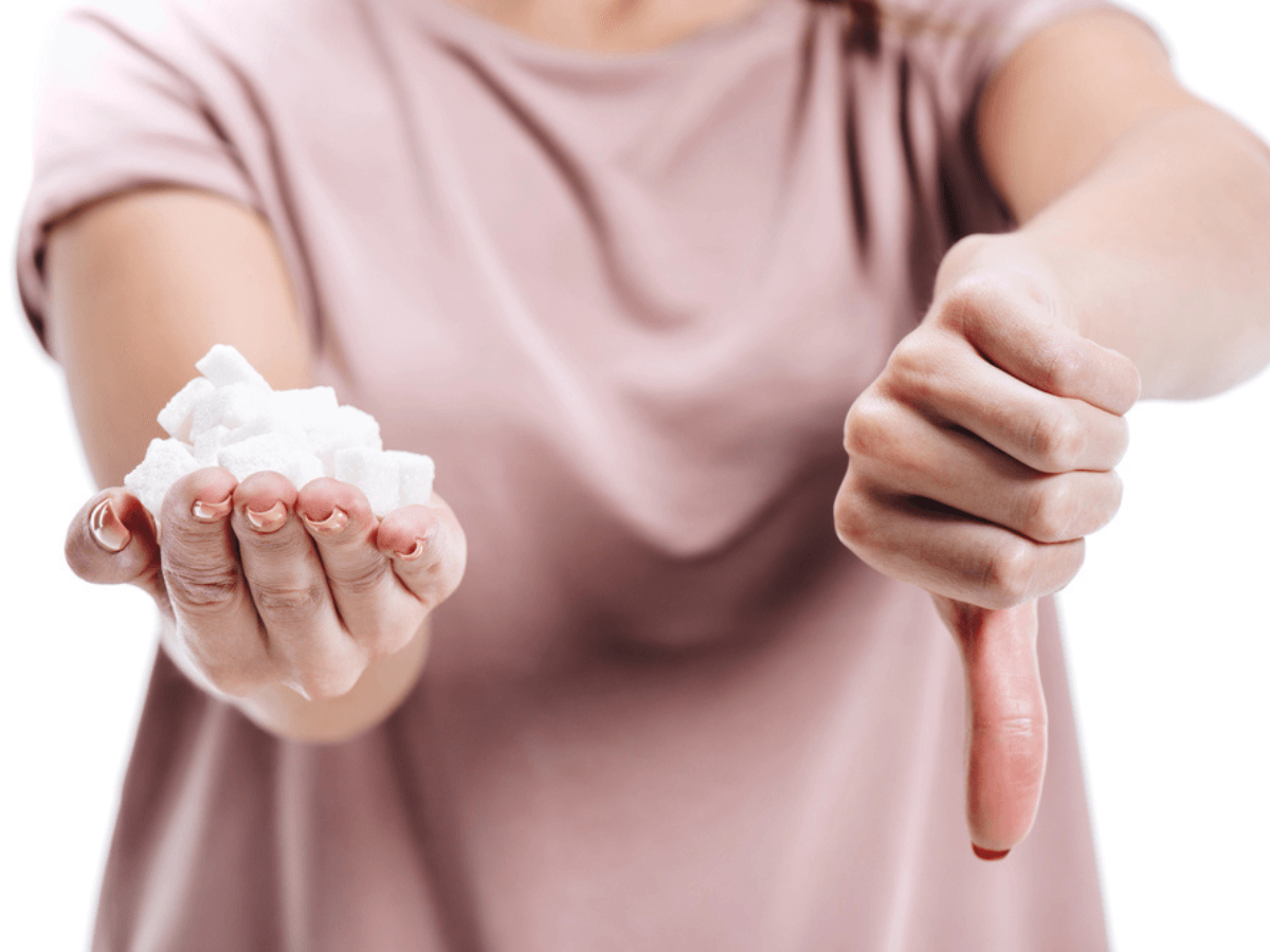 Woman holding a sugar wiht the left hand doing thumbsdown