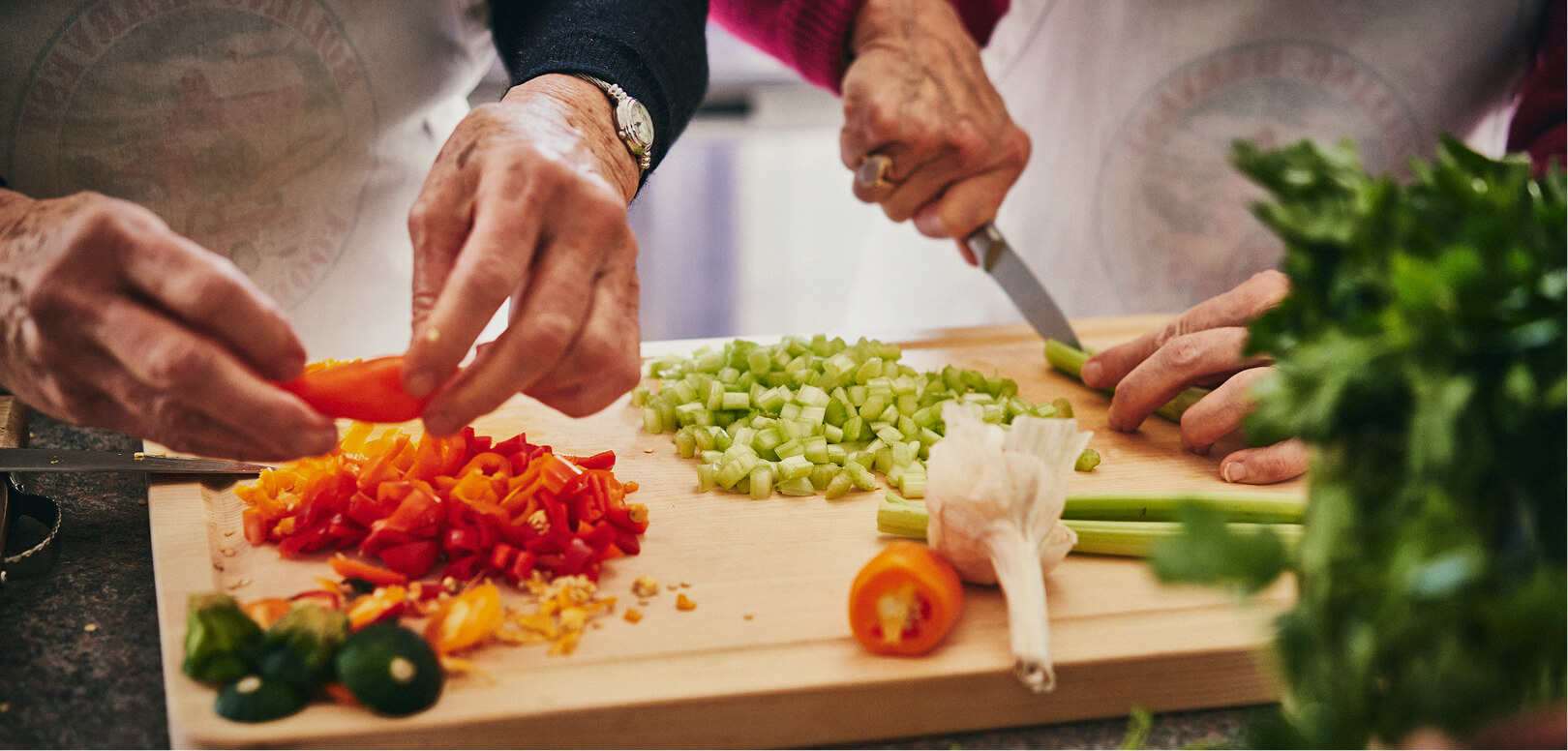 A photo of hands holding and cutting vegetables