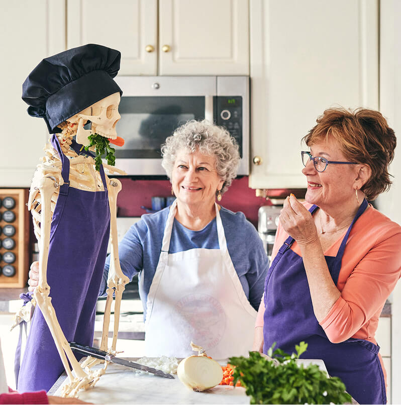 Irma Feeding Skelly with Vicky smiling beside her.